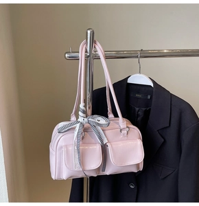 Close-up of pink shiny bowling bag featuring dual front pockets and plaid bow detail