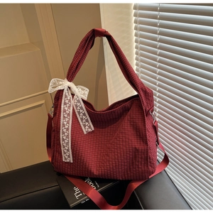 Detail of red checkered canvas tote bag featuring white lace bow and wide strap