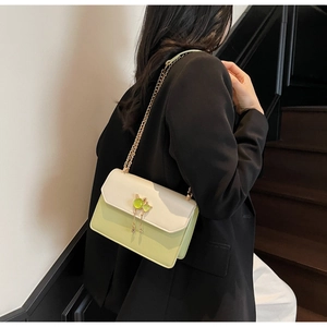 Gros plan d'un petit sac carré vert citron avec fermoir chat doré et pompon chic