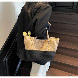 Detail of two-tone straw tote bag showing woven texture and decorative tassel with beads