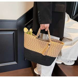 Detail of a large two-tone woven tote bag with a stylish tassel and tulip decoration
