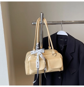 Close-up of beige leather bowling bag with a decorative lace bow hanging on a rack