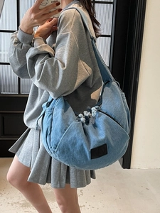 Chic blue denim crossbody dumpling bag with drawstring closure and tassel detail