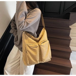 Canvas tote bag with large capacity utility pockets shown on model on stairs