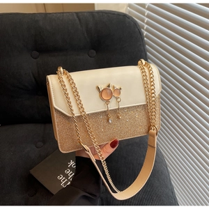 Détail du sac à paillettes avec breloque chat en opale et bandoulière dorée