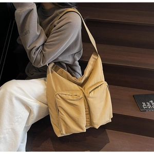 Detail of large khaki canvas tote bag with front zipper pockets and wide shoulder strap