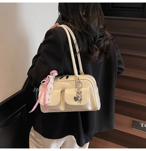 Close-up of creamy white shoulder bag with decorative charms on a wooden staircase