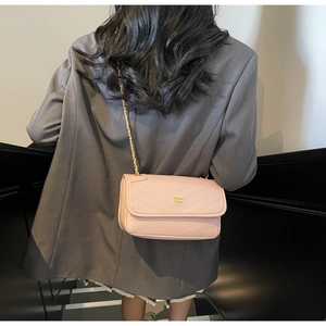 Close-up of pink chevron quilted handbag with gold chain strap and metal logo detail
