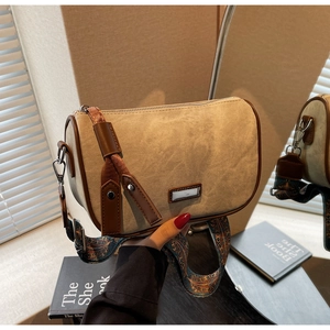 Close-up of beige pillow bag featuring brown leather trim and retro printed wide strap
