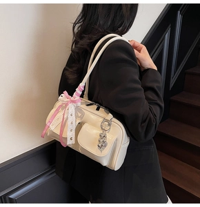 Detailed view of cream leather shoulder bag with cute lace bow and heart charm decoration