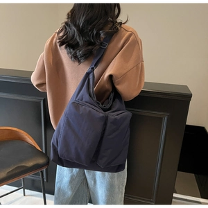 Detail of navy blue puffer tote bag featuring double front pockets and nylon texture