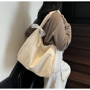 Close-up of cream tote bag featuring textured fabric and delicate white lace bow details