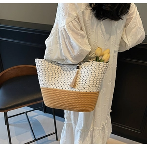 Detail of woven tote bag with contrast two-tone straw design and wooden bead tassel