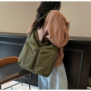 Detail view of large olive green canvas tote bag with dual front zipper pockets and wide strap