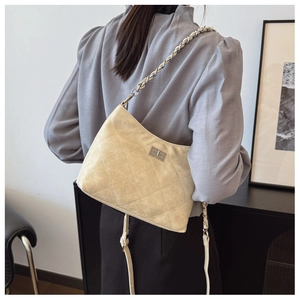 Detail der cremefarbenen Stepptasche mit silbernem Drehverschluss und Kettenriemen