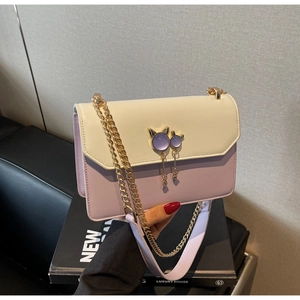 Détail du sac bicolore avec bijou de sac chat doré et bandoulière chaîne