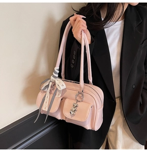Detail of pink shoulder bag featuring front pockets and a cute bow charm accessory