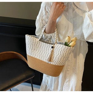 Detail of woven straw tote bag with polka dots, dual-tone texture, and tassel charm