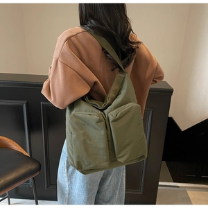 Detail of army green canvas tote bag featuring dual front pockets and wide shoulder strap
