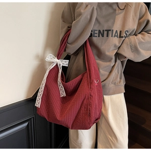 Detail view of red plaid tote bag with delicate white lace bow accent and woven texture