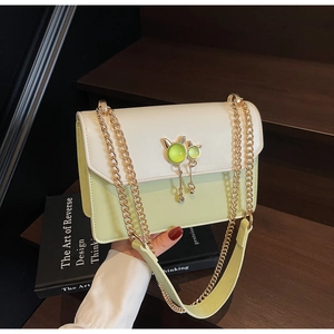 Détail du sac bandoulière avec breloques chat en métal et pierres précieuses vertes