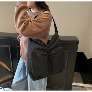Detail of black nylon tote bag featuring double front zipper pockets and wide shoulder strap