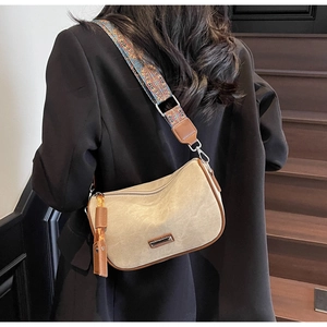 Close-up of cream canvas pillow bag with brown leather trim and ethnic style wide strap