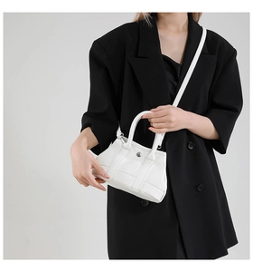 Detailed macro view of white lychee-patterned leather and silver metal buckle on bucket bag