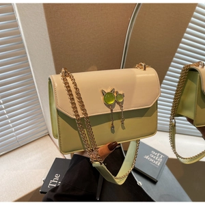 Détail du sac à rabat bicolore vert avocat avec fermoir chat et chaîne dorée élégante