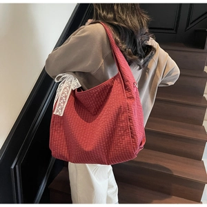 Detail of red checkered tote bag with a white lace bow charm on a soft hobo strap