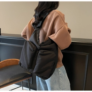 Close-up of large black nylon tote bag featuring dual front zipper pockets and strap