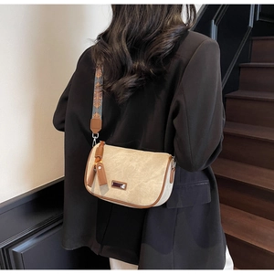 Detail of retro crossbody pillow bag with beige matte texture and jacquard strap
