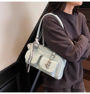 Detail of mint green shoulder bag showing two front flap pockets with heart and bow decor