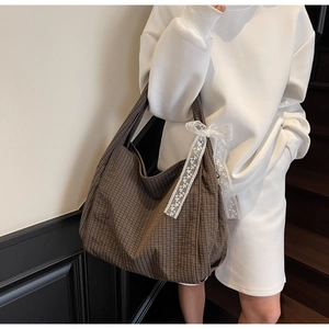 Detail of brown plaid tote bag with white lace bow and large capacity canvas texture