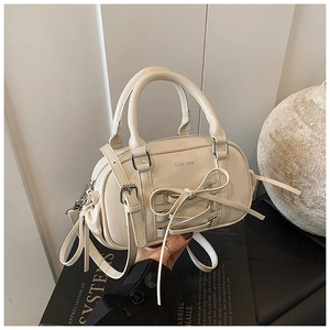 Close-up of cream patent leather Boston bag with ribbon bow and silver hardware detail