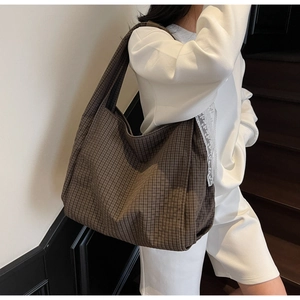 Detail of the brown checked pattern on a large capacity canvas tote bag worn by model