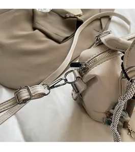 Detail of silver metallic zipper and woven rope pendant on a beige crossbody handbag
