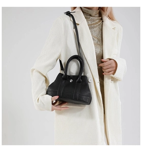 Detail of black lychee grain leather mini handbag with silver hardware and shoulder strap