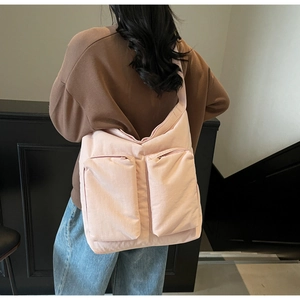 Detail of light pink tote bag featuring dual zipper front pockets and wide shoulder strap
