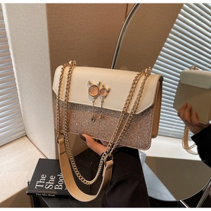 Détails du sac avec paillettes dorées, breloques de chat et pompons élégants