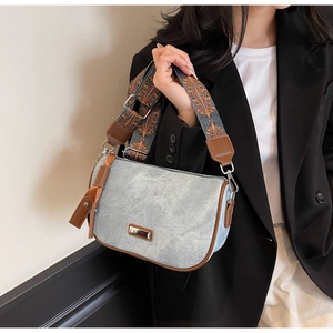 Detail of light blue pillow bag with brown trim and ethnic style woven wide strap
