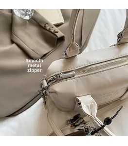 Detail of silver zipper and embossed letters on cream minimalist handbag for women
