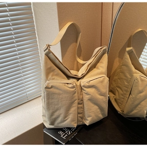Macro detail of beige tote bag with two zippered front pockets and wide shoulder strap