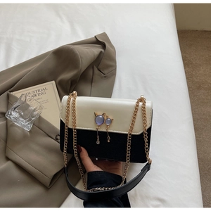Détail du sac bandoulière bicolore avec pendentifs chat violets et chaîne dorée