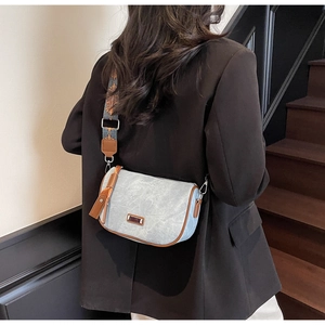 Close-up of textured light blue crossbody bag with geometric embroidered wide strap