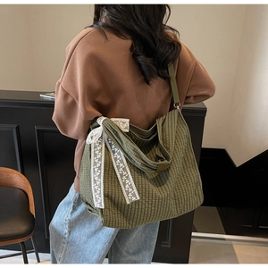 Detail showing dark green checkered tote bag with a delicate white lace bow decoration