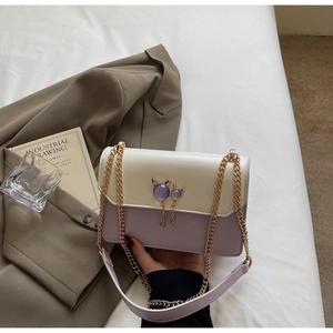 Détail du sac bandoulière bicolore crème et violet avec fermoir chat doré élégant