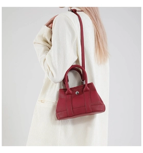 Detail view of the deep red litchi grain leather texture and silver buckle on the bag