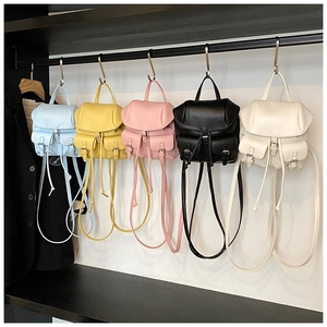 Five assorted colors of mini PU leather backpacks hanging on a metal rack display