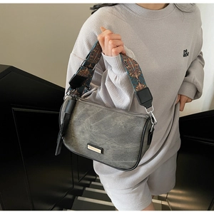 Detail of grey canvas crossbody bag featuring a bohemian embroidered wide shoulder strap